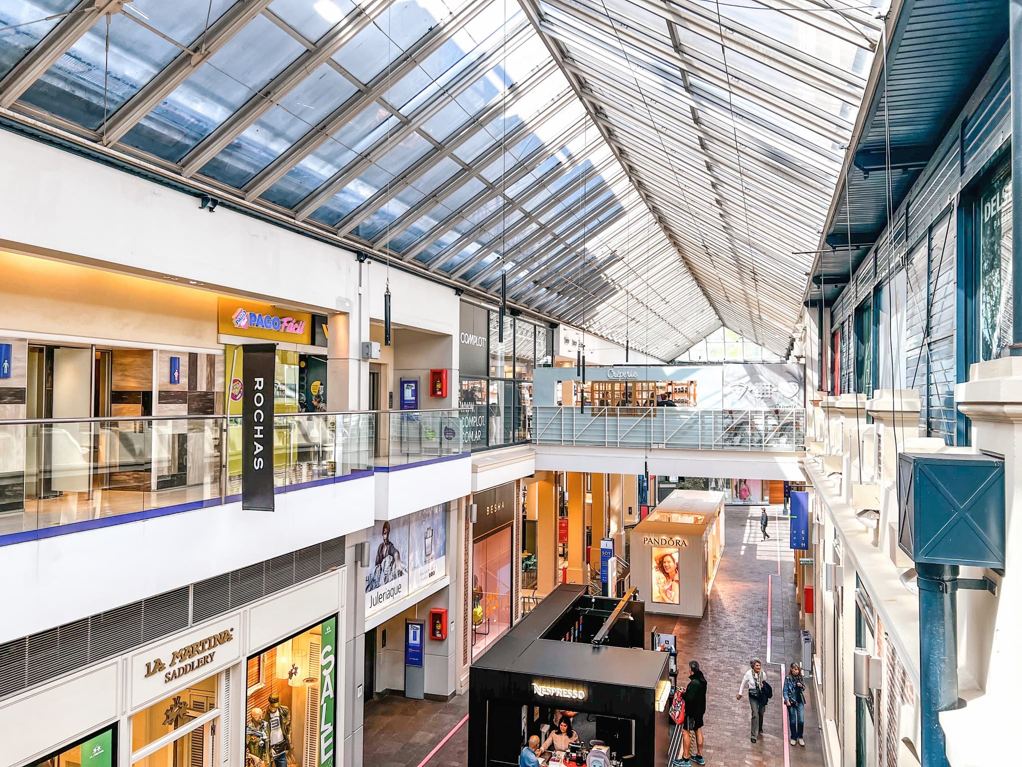 Interior de El Solar Shopping con techo vidriado y locales en dos niveles