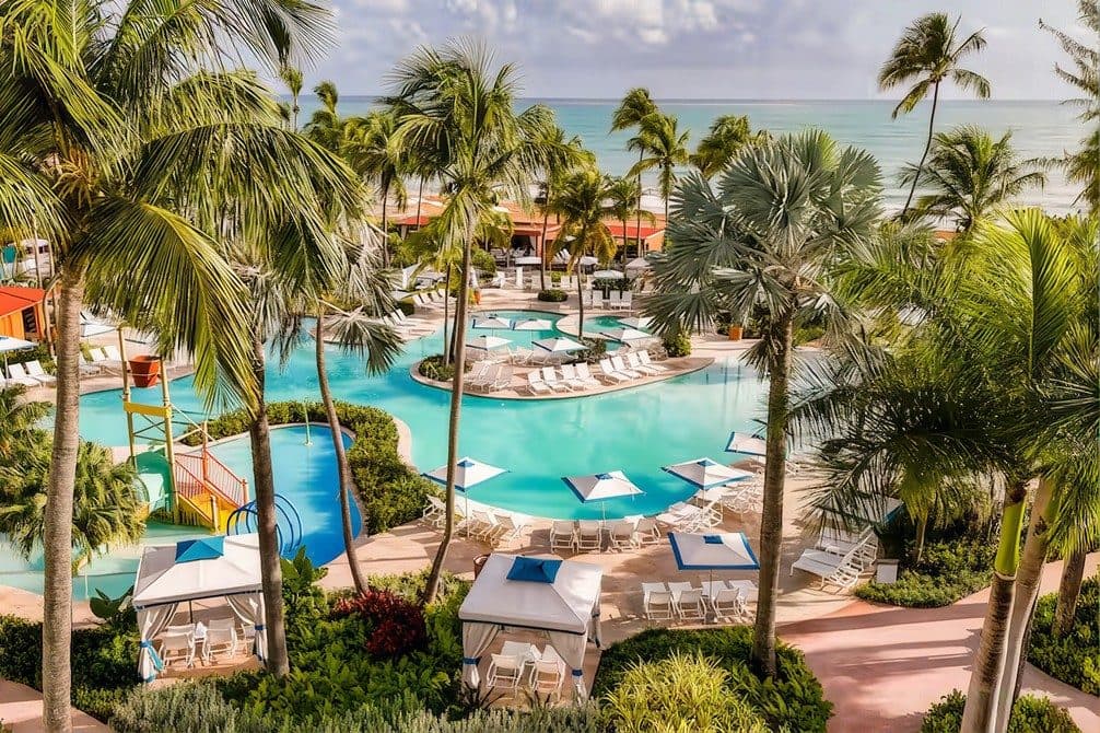 Piletas de un resort Wyndham rodeadas de palmeras frente al mar